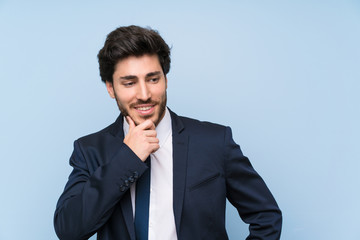 Businessman over isolated blue wall looking to the side