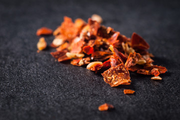 Universal shredded red peppers with seeds on a dark background close-up