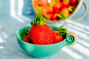 rote erdbeeren in einer schüssel, im hintergrund erdbeeren im sieb zum waschen