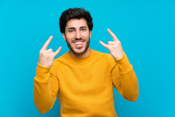 Naklejka premium Handsome over isolated blue wall making rock gesture
