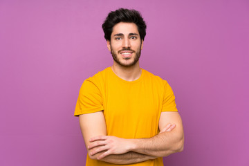 Handsome over isolated purple wall keeping the arms crossed in frontal position