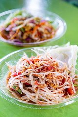 Papaya salad or Som Tum in Thai foods with Shrimp or Prawn and vegetable on Green wooden table background.