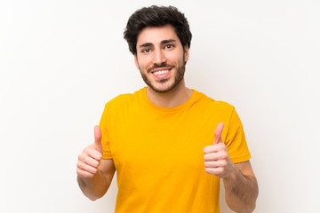 Handsome over isolated white wall giving a thumbs up gesture