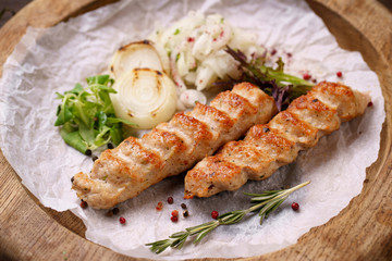 Traditional Adana kebab on wooden plate with marinated onion garnishing and spicy aromatic herbs. Delicious meat, Turkish cuisine