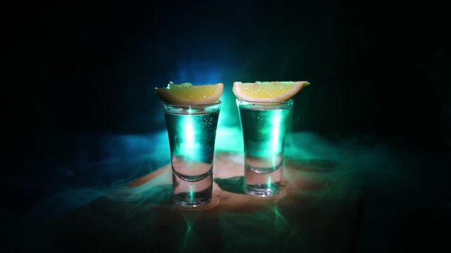 Club drink concept. Tasty alcohol drink cocktail tequila with lime and salt on vibrant dark background or glasses with tequila at a bar. Selective focus