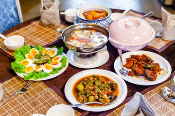 Group of Foods, Boiled Eggs with Fish Sauce, Fried Spicy Fish and Spicy Stir Fried Slice Eggplant and Pork Boiled Soup a Healthy Food Thai Food on Thai Decorate Table.
