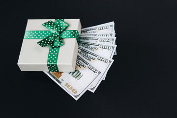 Gift box with dollar bills on black background.