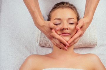 Obraz na płótnie Canvas Young woman enjoys ayurvedic facial massage in luxury resort dark lighting