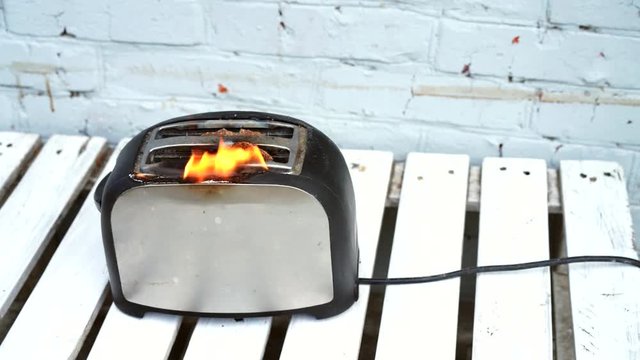 Burning toaster. Toaster with two slices of toast caught on fire over white background. Danger of careless handling of electrical appliances. Fire