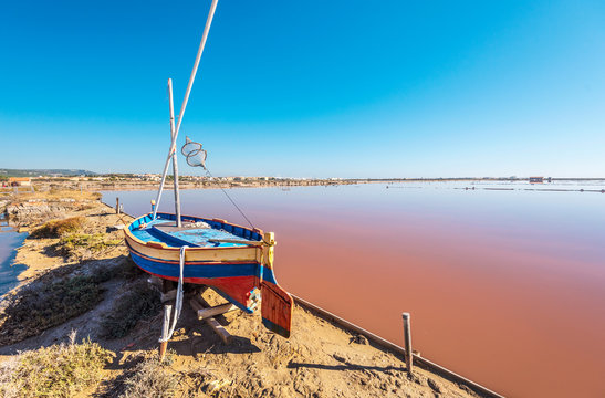 Saline island of Saint Martin de Gruissans, the old wooden ship at left and the reddish colored saturated with salt water at right.  Occitanie, France.