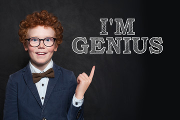 Happy redhead child in glasses and suit on black background