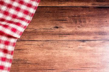 Checkered red napkin on an old wooden brown background, top view. Image with copy space. Kitchen table with a towel - top view with copy space. 