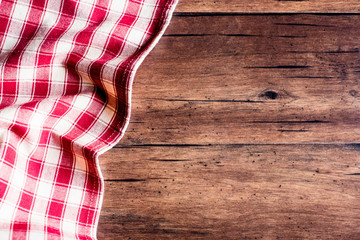 Checkered red napkin on an old wooden brown background, top view. Image with copy space. Kitchen table with a towel - top view with copy space. 