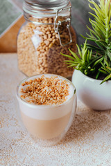 glass of latte coffee on light table with almond nuts