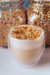 glass of latte coffee on light table with almond nuts