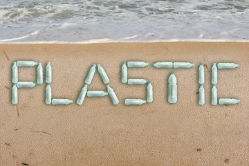 Bottles on the beach form the inscription PLASTIC. Pollution of the World ocean by plastic waste