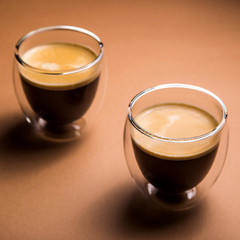 Black coffee with froth in modern cups on a plain background