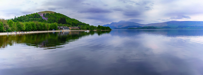 Panoramic image of beautiful tranquil scenery of Loch Lomond in Luss with reflection , Scotland