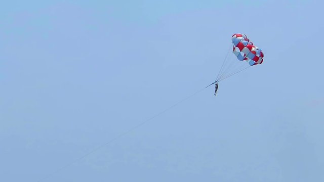Girl doing parasailing high in the blue sky