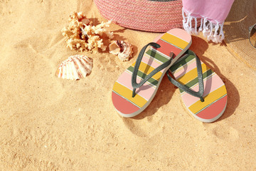 Fototapeta na wymiar Flip flops and other beach accessories on sand, above view with space for text