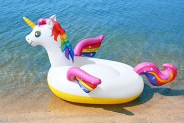 Funny inflatable unicorn ring near sea on sunny day