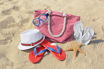 Set of different stylish beach accessories on sand