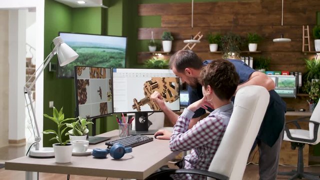 Two architects are working in creative agency. They are looking at new gear prototype in CAD or 3D software