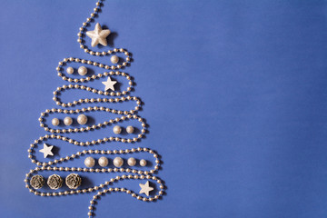 Christmas tree concept with silver bead chain, silver stars, cones and globules on dark blue background, deep shadows - text space