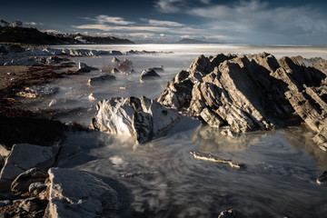 close up on beautiful sandy beach with rocks on atlantic coast in bidart in long exposure in beautiful sunny morning, basque country