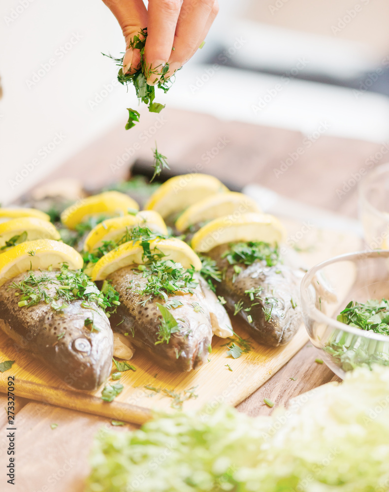 Wall mural Chef putting greenery on fish with lemons.