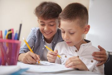 Friendship, childhood, leisure activities concept. Close up of two adorable young boys enjoying drawing together. Lovely schoolboys doing art class assignment - obrazy, fototapety, plakaty