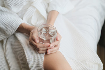 woman holding water glass on the bed after wake up, healthy concept.