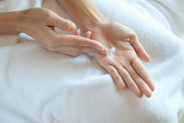 Obraz na płótnie Canvas Woman applying moisturizing cream/lotion on hands, beauty concept.