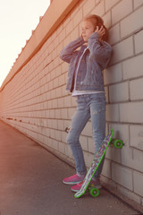 Teen on skateboard in jeans clothes, on the background of industrial	
