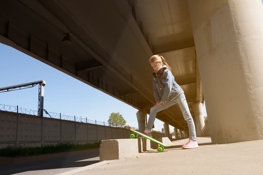 Teen on skateboard in jeans clothes, on the background of industrial	