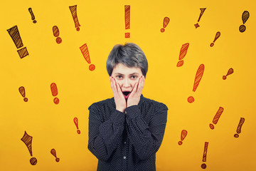 Shocked female keeps hands on cheeks and mouth open, receives bad news, exclamation marks like different thoughts escaping from head.