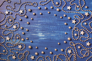 Christmas decoration with silver bead chain and stars on dark blue wooden background - place for text in the middle