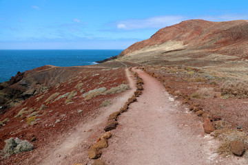 Montana Roja (Red mountain) path in volcanic area with red rocks and soil, ground lava field, El...