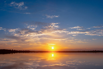 Sunset reflection lagoon. beautiful sunset behind the clouds and blue sky above the over lagoon landscape background. dramatic sky with cloud at sunset