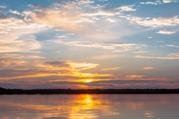 Obraz premium Sunset reflection lagoon. beautiful sunset behind the clouds and blue sky above the over lagoon landscape background. dramatic sky with cloud at sunset