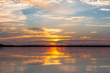 Naklejka na ściany i meble Sunset reflection lagoon. beautiful sunset behind the clouds and blue sky above the over lagoon landscape background. dramatic sky with cloud at sunset