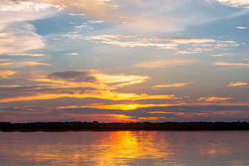 Sunset reflection lagoon. beautiful sunset behind the clouds and blue sky above the over lagoon landscape background. dramatic sky with cloud at sunset