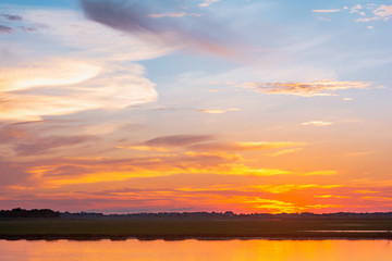 Sunset reflection lagoon. beautiful sunset behind the clouds and blue sky above the over lagoon landscape background. dramatic sky with cloud at sunset
