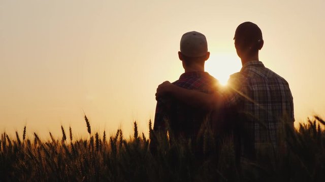 Two young men hugging against the backdrop of the sunset, looking forward to the horizon