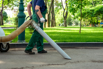Cleaner man  cleans the sidewalk with a blower in the park