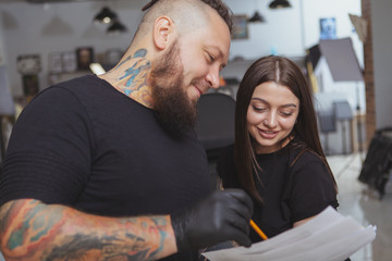 Cropped shot of a beautiful cheerful young woman smiling, deciding which tattoo she wants at tattoo...