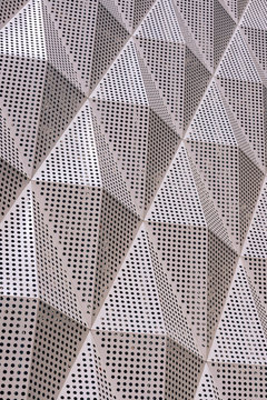 Metal facade of the building. Texture of embossed metal surface with holes. Walk along Arbat street in the city of Shymkent.
