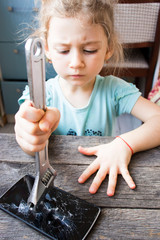 evil little girl breaks a smartphone with a wrench