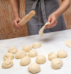 Girl rolls the dough in the kitchen