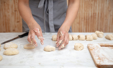 The hostess cuts the dough in the kitchen